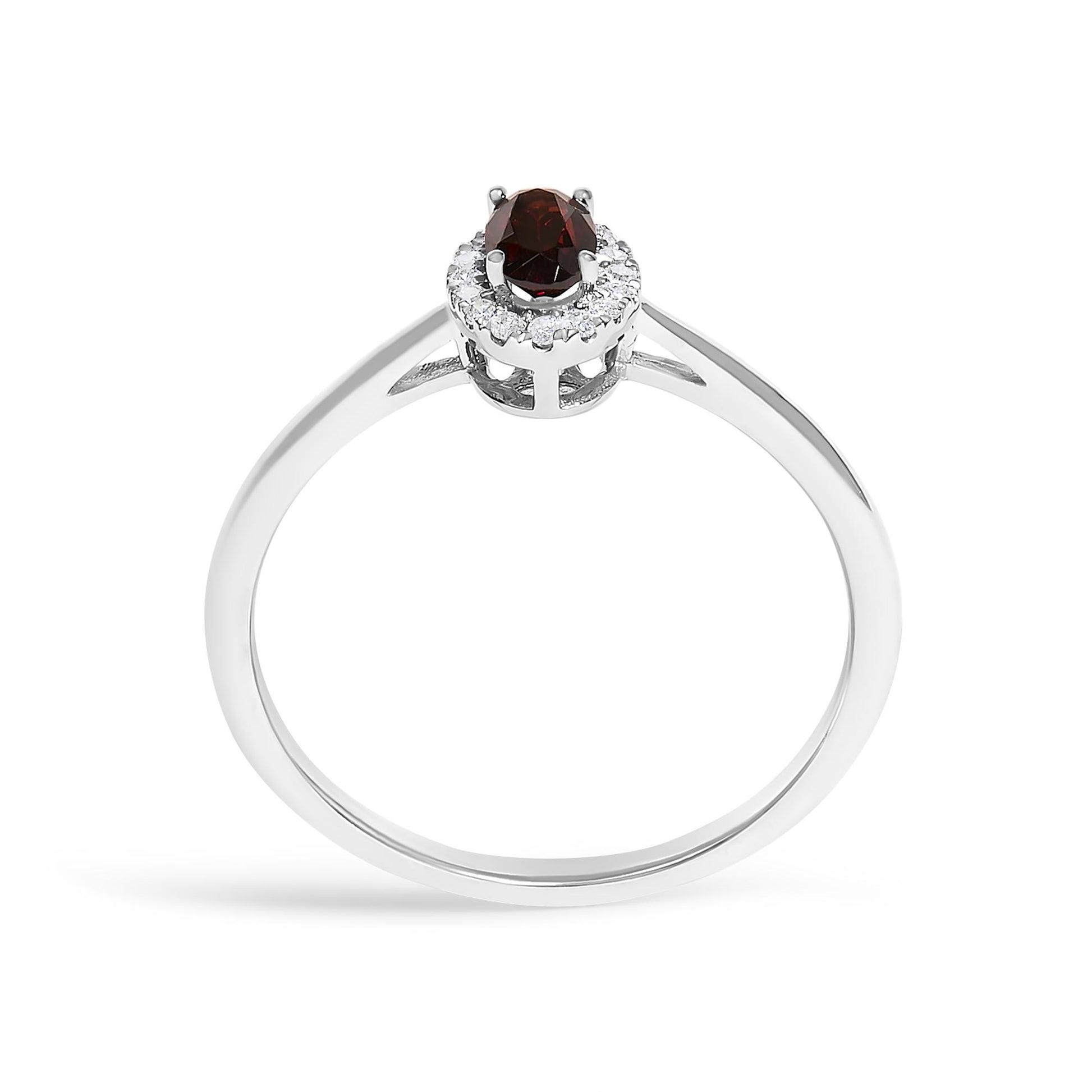 White metal ring shown from the top angle with an oval red gemstone in prong setting surrounded by round white gemstones in a micro-pave setting.