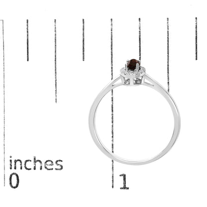 White metal ring shown on a scale from side angle featuring one oval red gemstone in prong setting surrounded by small round white gemstones in micro-pave setting.