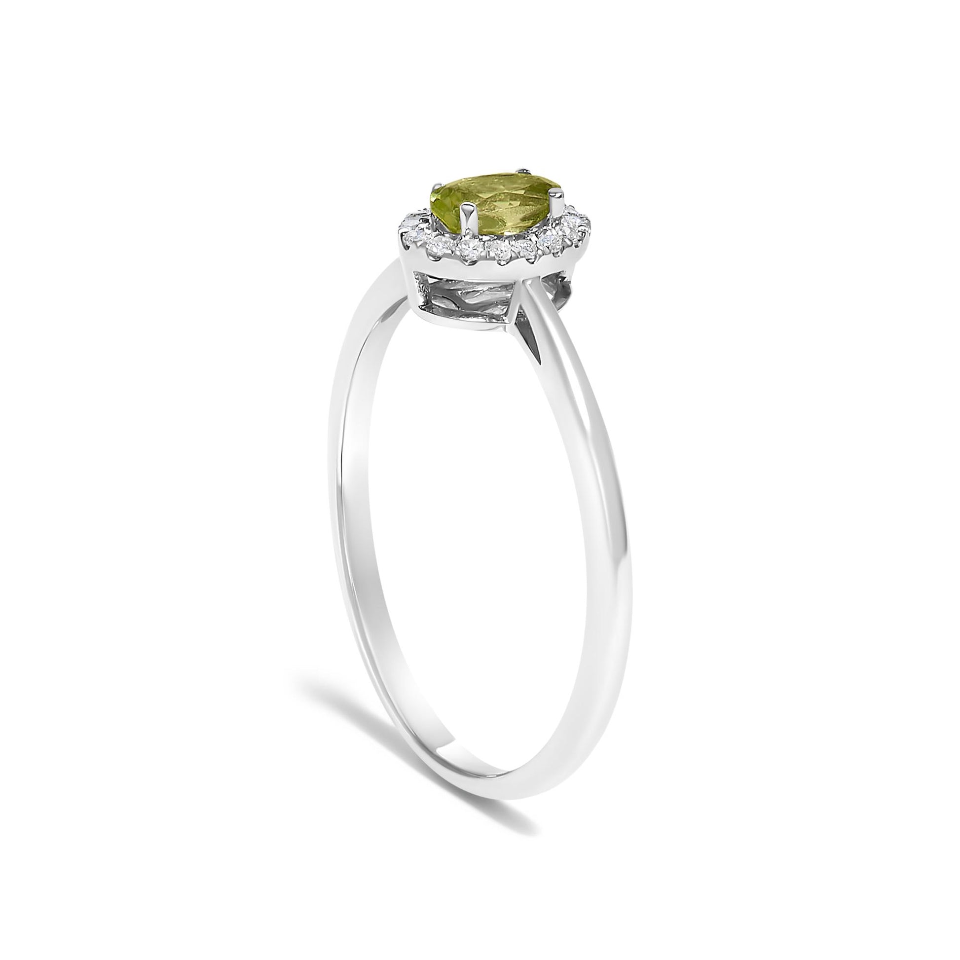 White metal ring shown in a side view featuring an oval green gemstone in a prong setting surrounded by a halo of small white gemstones in micro-pave setting.