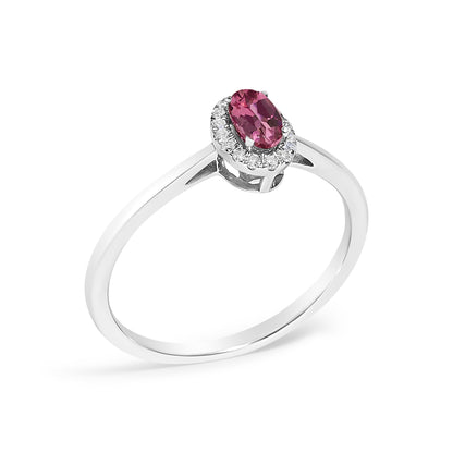 White metal ring with an oval pink gemstone in prong setting surrounded by a halo of small white gemstones in micro-pave setting, shown from a slightly elevated angle on a white background.
