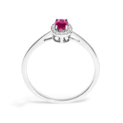 Front angle view of a white metal ring featuring a red oval gemstone in a prong setting, surrounded by small white round gemstones in a micro-pave setting.