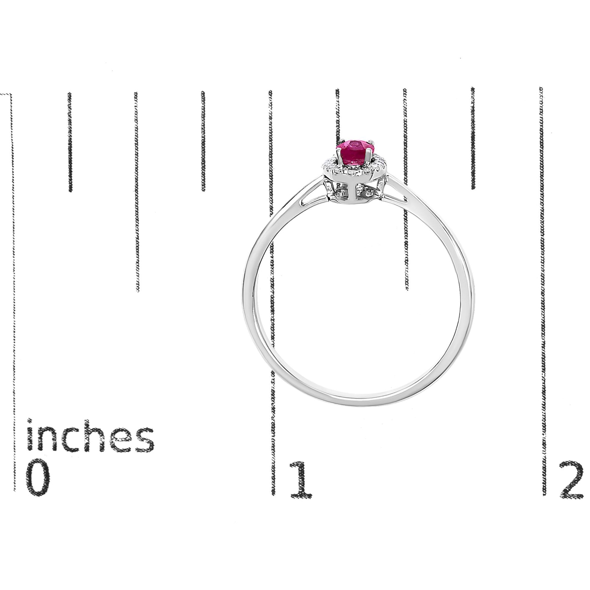 White ring with a red oval gemstone center and surrounding white round gemstones in micro-pave setting, shown from the side on a scale.