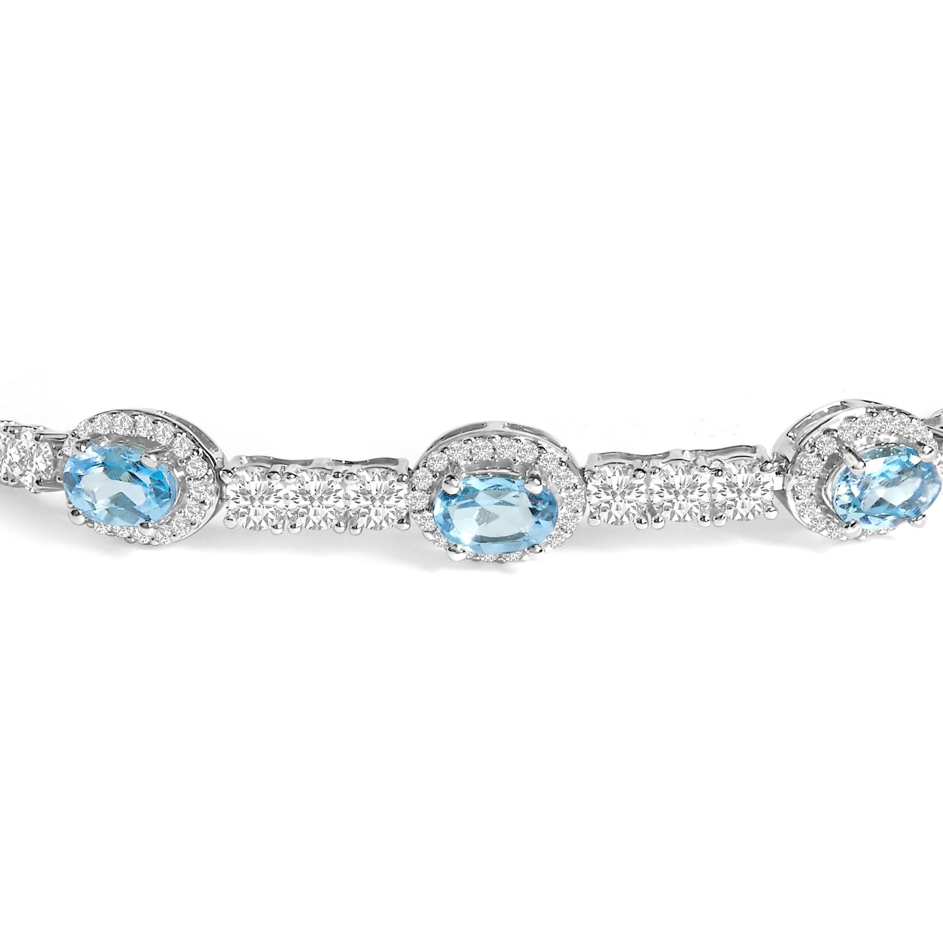 Close-up front angle of a white bracelet featuring oval blue gemstones surrounded by clusters of small white round gemstones in prong settings.