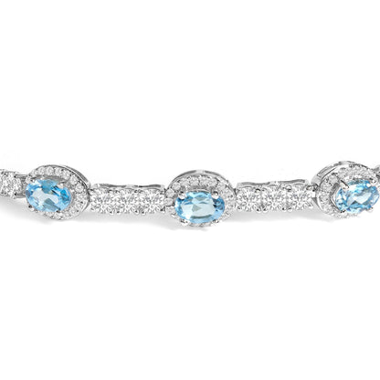 Close-up front angle of a white bracelet featuring oval blue gemstones surrounded by clusters of small white round gemstones in prong settings.