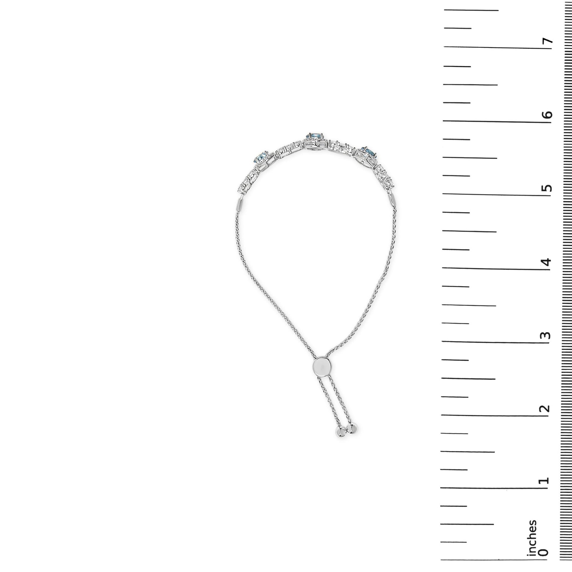 White metal bracelet with oval blue gemstones and round white gemstones in prong settings, shown on a scale, front angle.