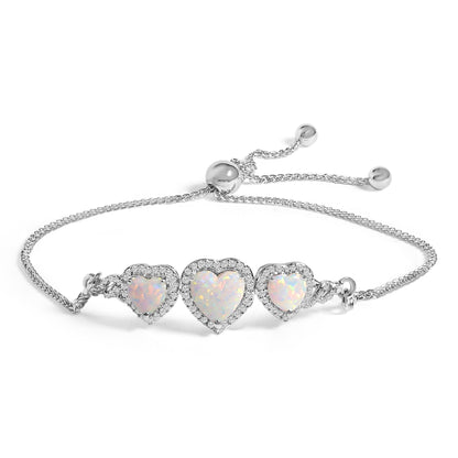 White metal bracelet with three heart-shaped white opal gemstones surrounded by small round white gemstones, shown at a slight angle on a white background.