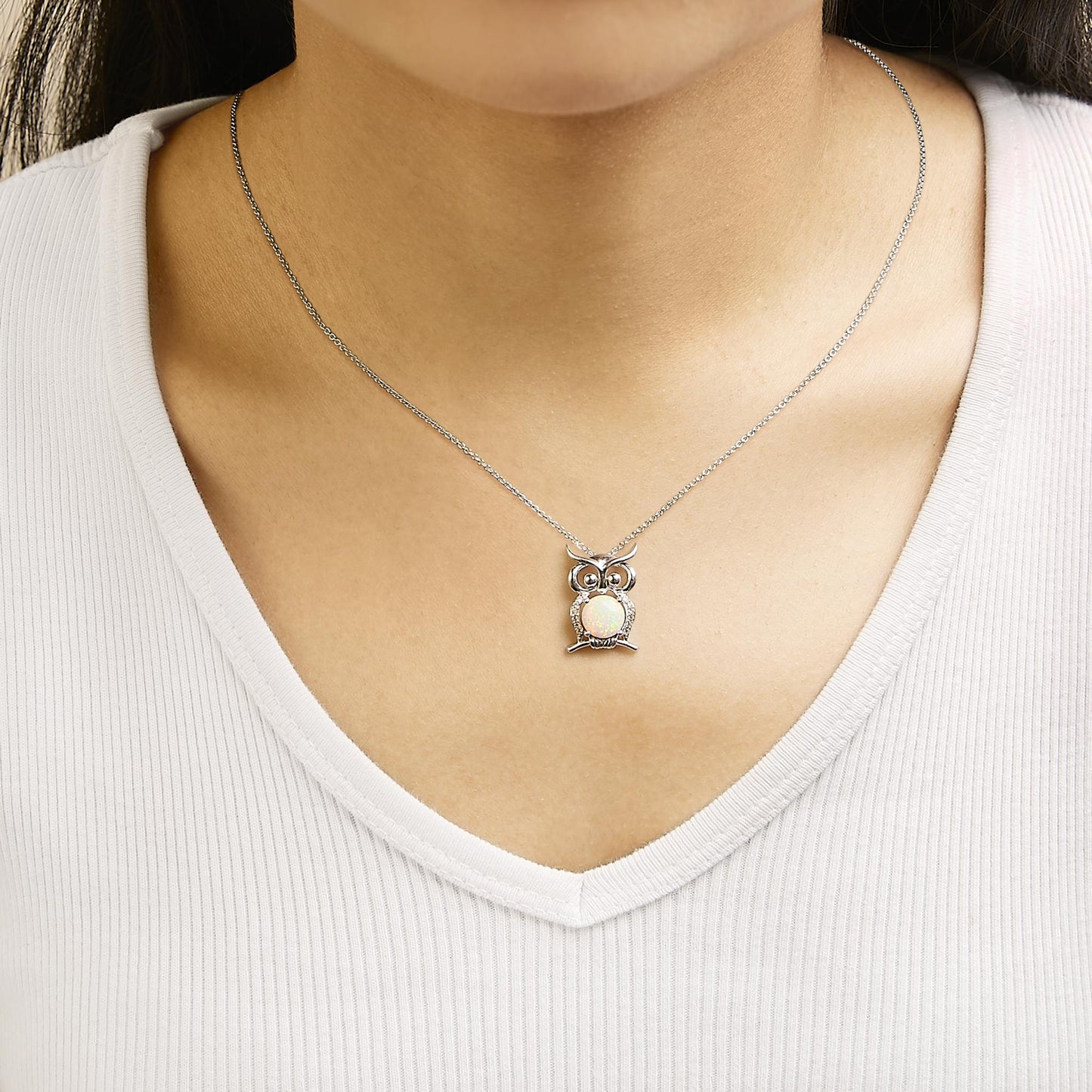 Necklace with an owl-shaped pendant featuring a central round white opal gemstone and multiple small round white gemstones on the owl, shown worn on a model from the front.