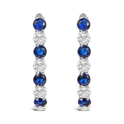 Pair of white metal earrings shown from the front, featuring a vertical row of alternating blue and white round gemstones in shared prong settings.