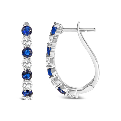 Front and side views of a pair of white metal hoop earrings with alternating blue and white round gemstones in shared prong settings, shown on a white background.