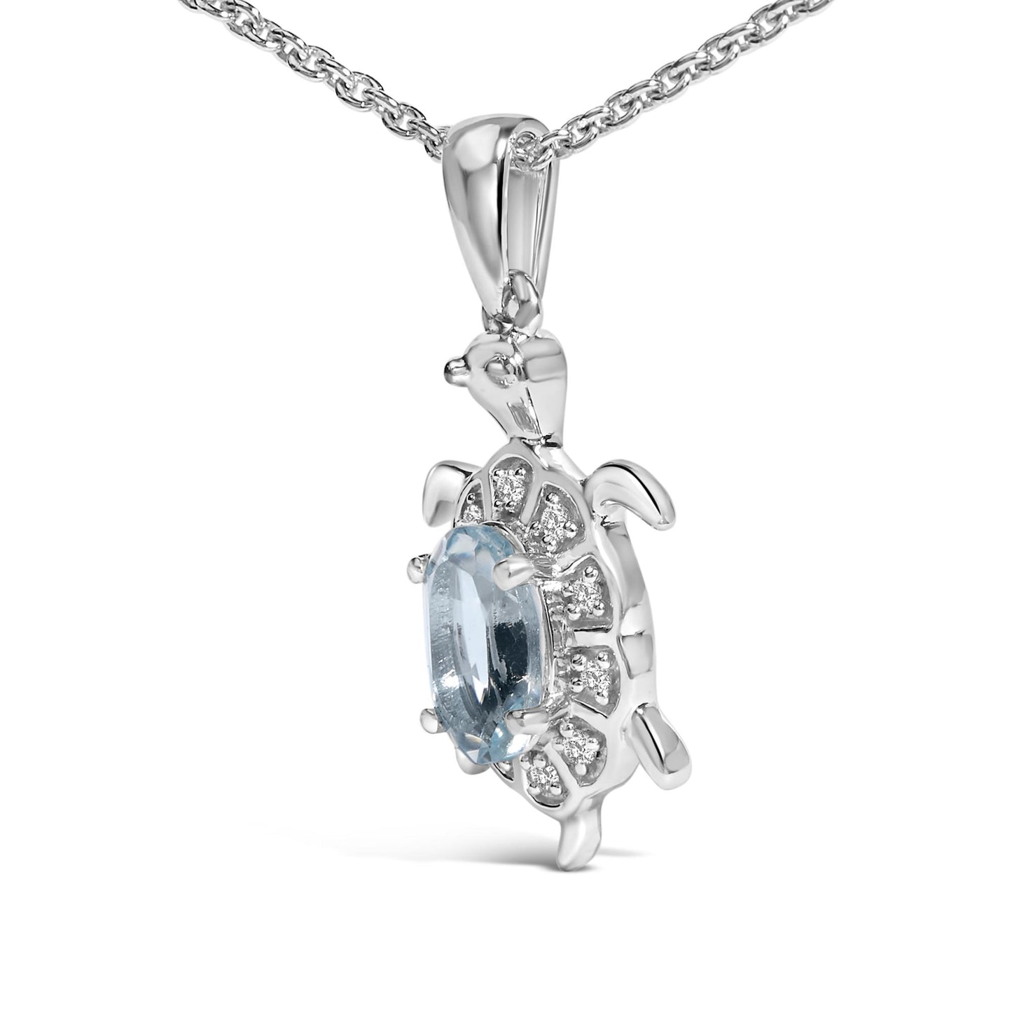 Close-up side angle of a white metal necklace pendant shaped like a turtle, featuring one oval blue gemstone in the center and multiple round white gemstones surrounding it, shown against a white background.