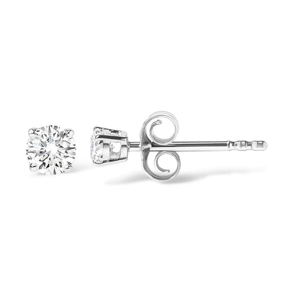 Close-up side view of white metal stud earrings with round white gemstones in 4-prong settings.