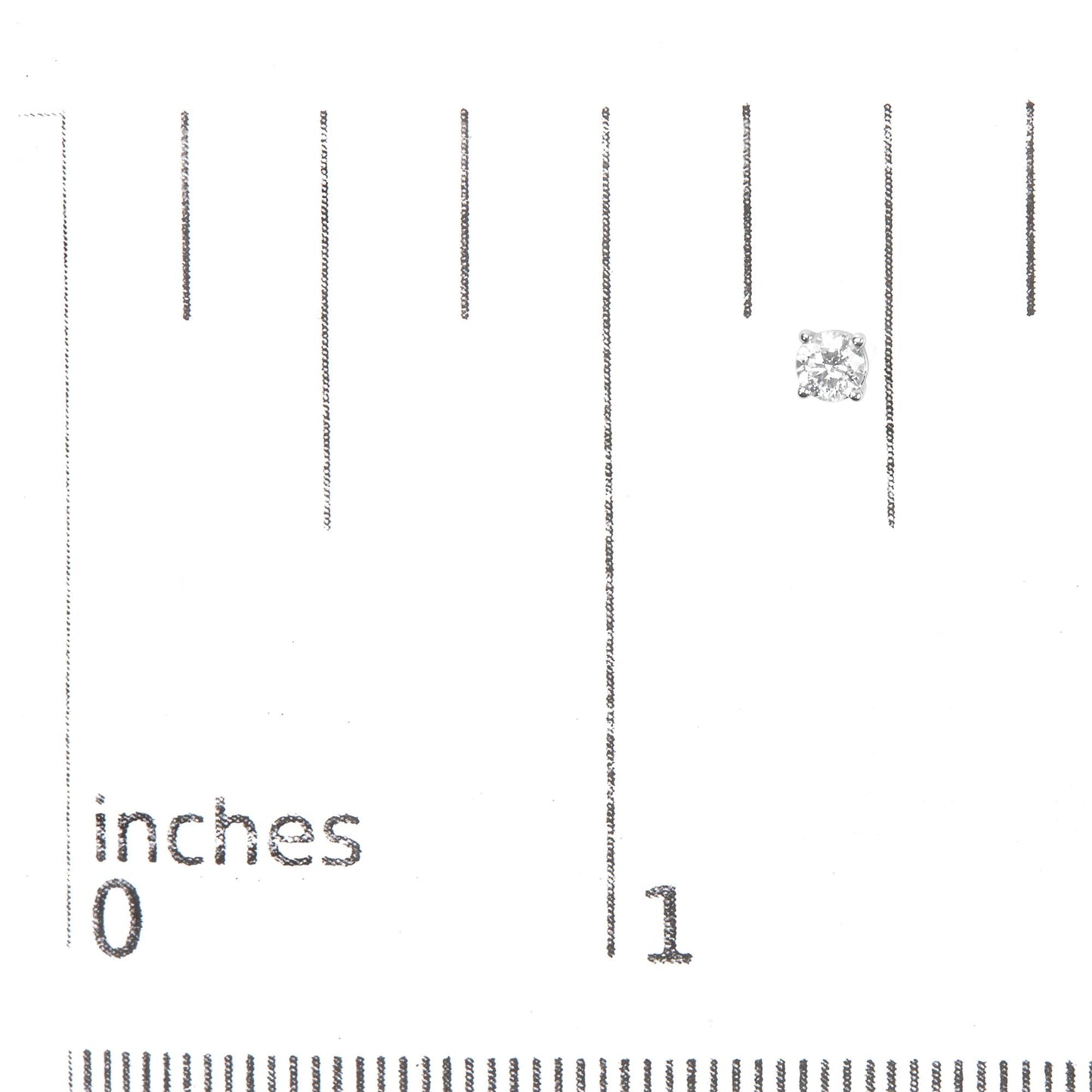 Single white metal stud earring with a round white gemstone in a four-prong setting, shown on a ruler for size reference, front angle.