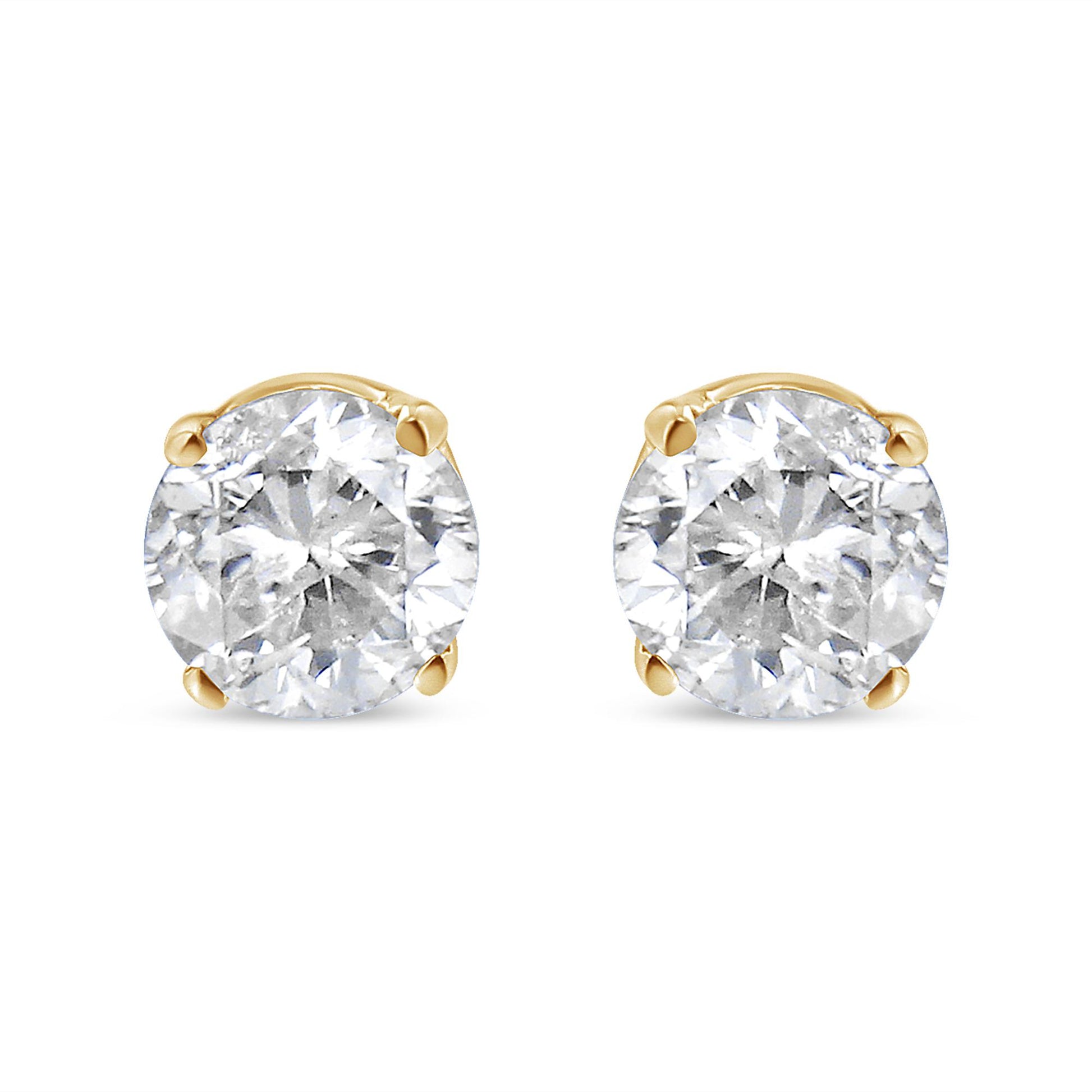 Pair of yellow metal stud earrings with round white gemstones in 4-prong settings, shown from a front angle.