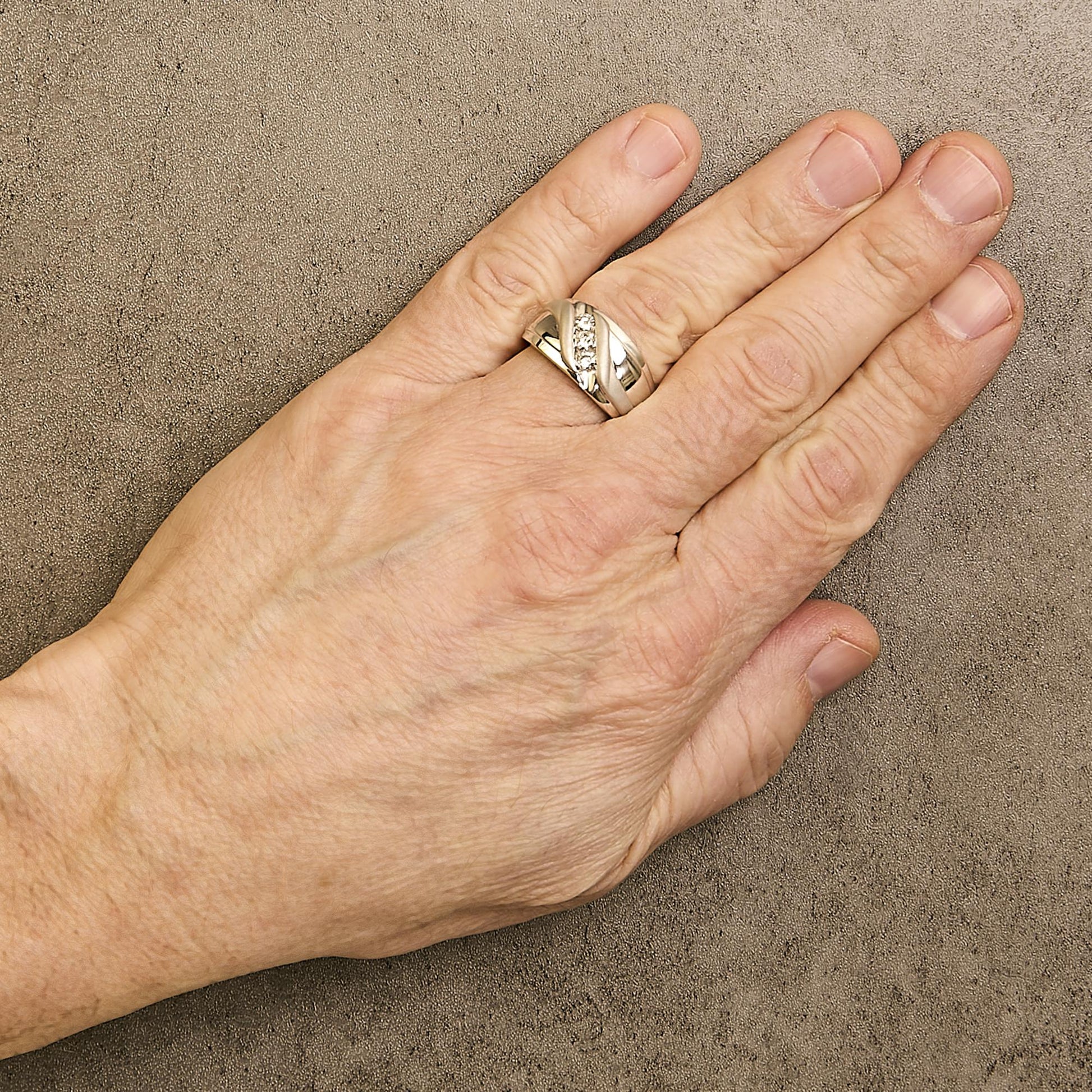 White ring with a crisscross design featuring three round white gemstones in a channel setting, shown worn on a model's finger from a top angle.