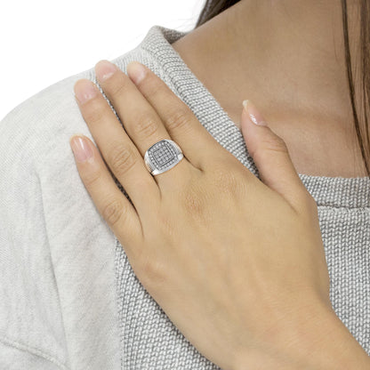 Close-up front angle of a white metal ring with round white gemstones in prong settings, worn on a model's hand resting on their chest.