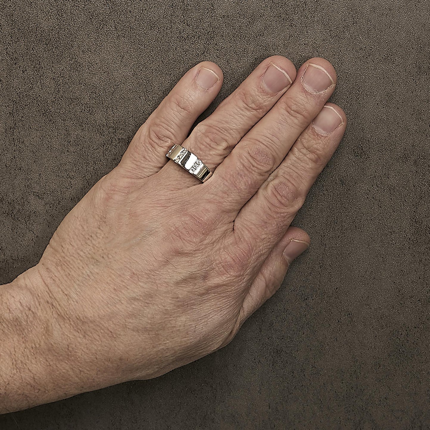 White metal ring with channel-set round white gemstones, shown worn on a model's finger from a top angle.