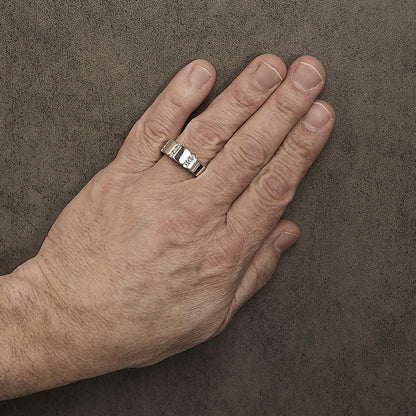 White metal ring with channel-set round white gemstones, shown worn on a model's finger from a top angle.