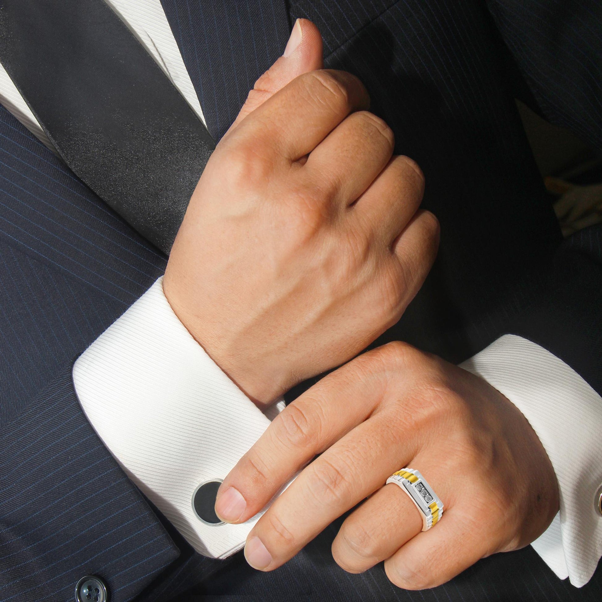 Ring with three round white gemstones in miracle setting, yellow and white metal band, shown on a model's hand from the top side angle.