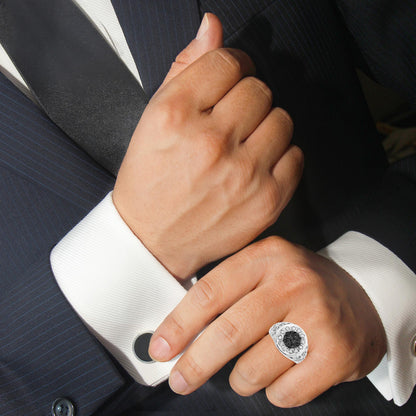 Close-up of a white metal ring with round black and white gemstones in prong settings, worn on a model’s finger, shot from an angled top view.