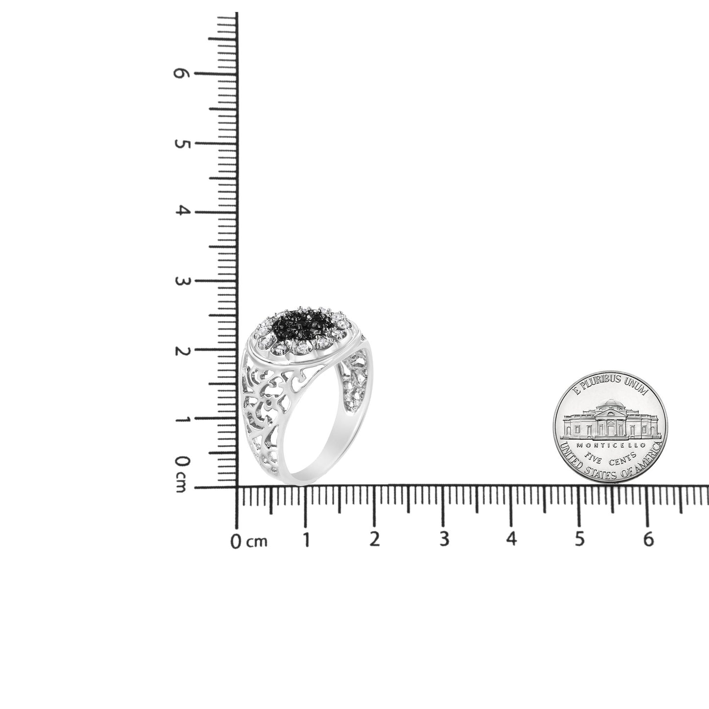 White metal ring with intricate openwork band, featuring a cluster of round black gemstones surrounded by round white gemstones in prong settings, shown at an angle on a ruler for size reference.