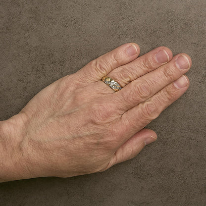 Yellow ring with intertwined bands featuring white round gemstones in prong settings, worn on a model's finger, shown from a top angle.