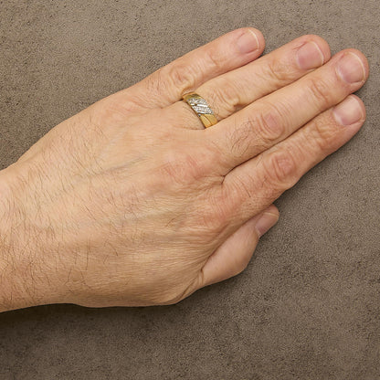 Yellow ring with two diagonal bands each set with round white gemstones in prong settings, shown worn on a model's finger, top view angle.