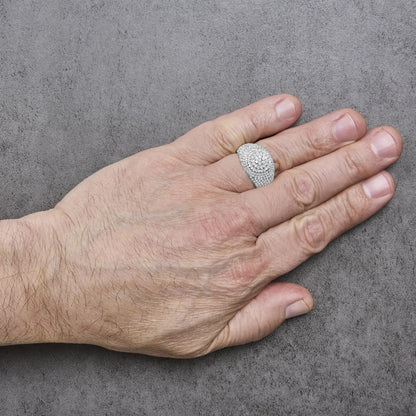 Yellow metal ring with round white gemstones in prong setting covering the top, shown worn on a model's finger from a top angle on a gray textured background.