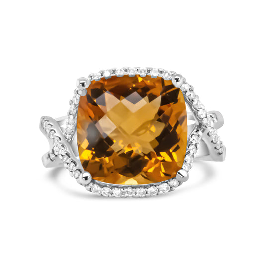 Front angle view of a white metal ring featuring a large yellow cushion-shaped gemstone in prong setting, surrounded by a band with round white gemstones in pave setting.