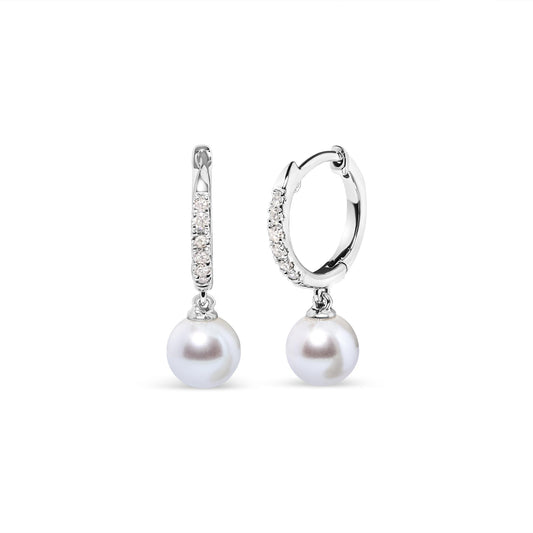Pair of white metal hoop earrings with small white gemstones in pave setting along the front, each featuring a round white dangling gemstone, shown in a front and angled side view on a white background.