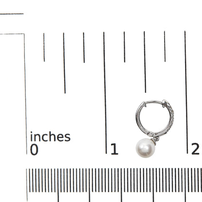 White metal hoop earring with pave-set white gemstones and a single round white pearl dangle, shown on a ruler for size reference, front angle.