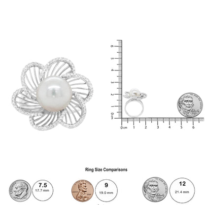 Top view of a white metal ring with a large central round white gemstone surrounded by open petal-shaped elements encrusted with small round white gemstones in pave setting, shown next to a ruler and coins for size reference.