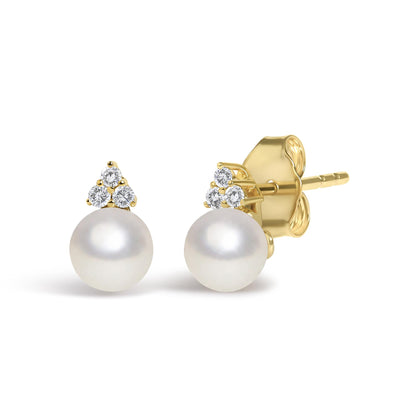 Close-up front and side angled view of a pair of yellow metal stud earrings featuring three prong-set round white gemstones forming a triangular shape above a round white pearl.