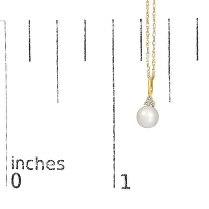 Close-up front angle of a yellow metal necklace shown on a scale, featuring a pendant with three prong-set round white gemstones above a large round pearl.
