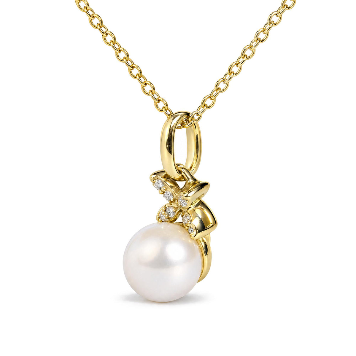 Close-up front angle of a yellow metal necklace chain with a large oval link and a dangling pendant featuring a large white pearl and a bow-shaped detail adorned with small white gemstones.