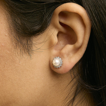 Close-up side view of a model wearing a white metal stud earring featuring a central round white gemstone surrounded by smaller white gemstones in a pave setting.