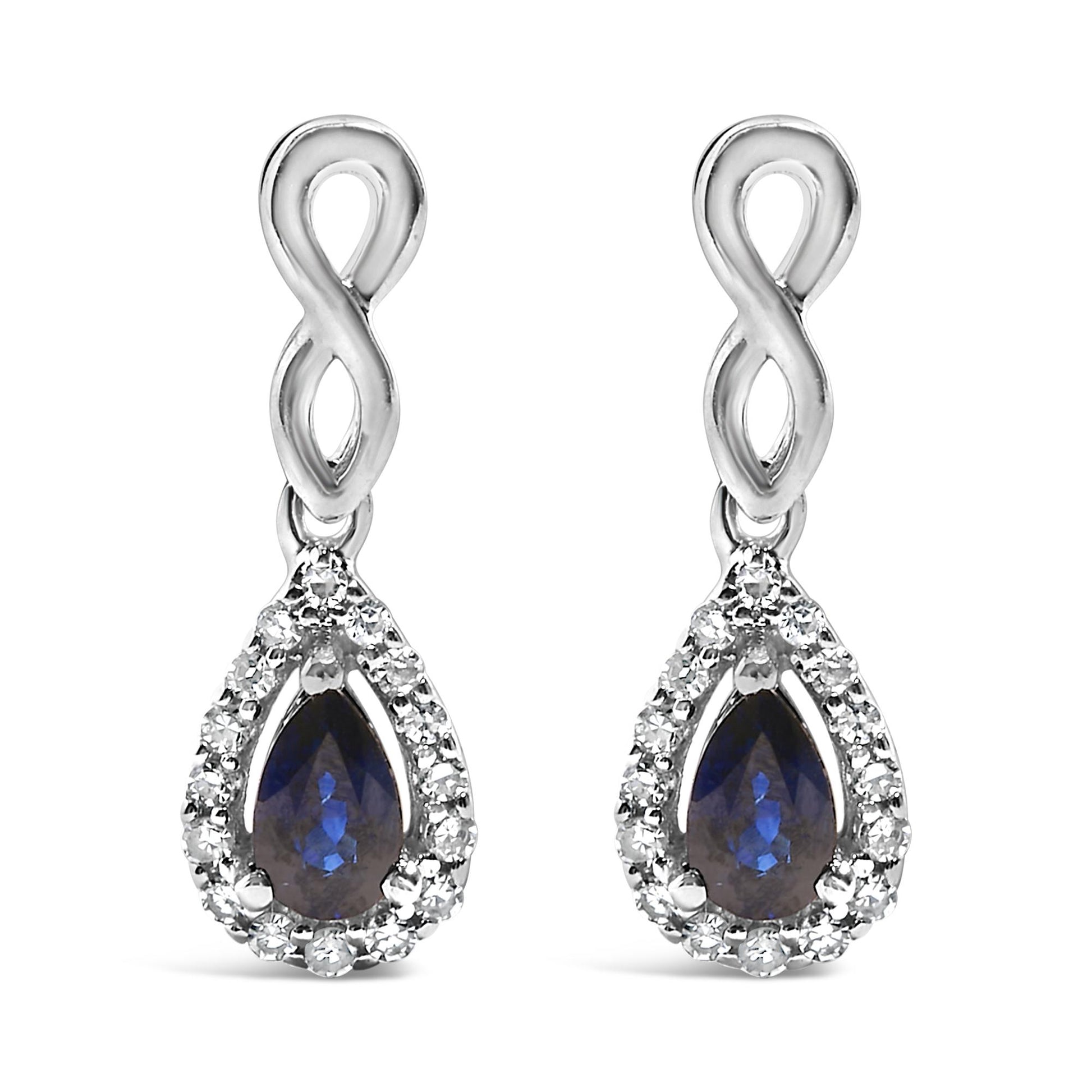 Front view of white metal infinity-shaped drop earrings with pear-shaped blue gemstones surrounded by a halo of small round white gemstones.