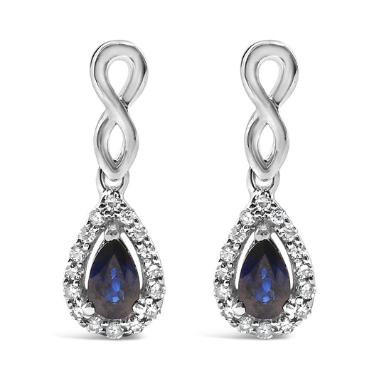 Front view of white metal infinity-shaped drop earrings with pear-shaped blue gemstones surrounded by a halo of small round white gemstones.
