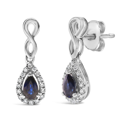 Pair of white metal earrings shown from front and side angles, featuring an infinity loop design with a teardrop-shaped blue gemstone surrounded by small white gemstones in a pave setting.