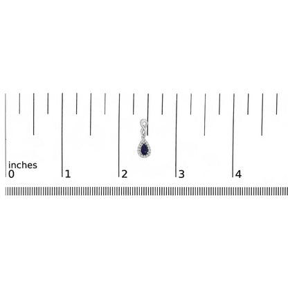 White metal earring with an infinity loop design and pear-shaped blue gemstone surrounded by small white gemstones, shown on a ruler scale from a front angle.