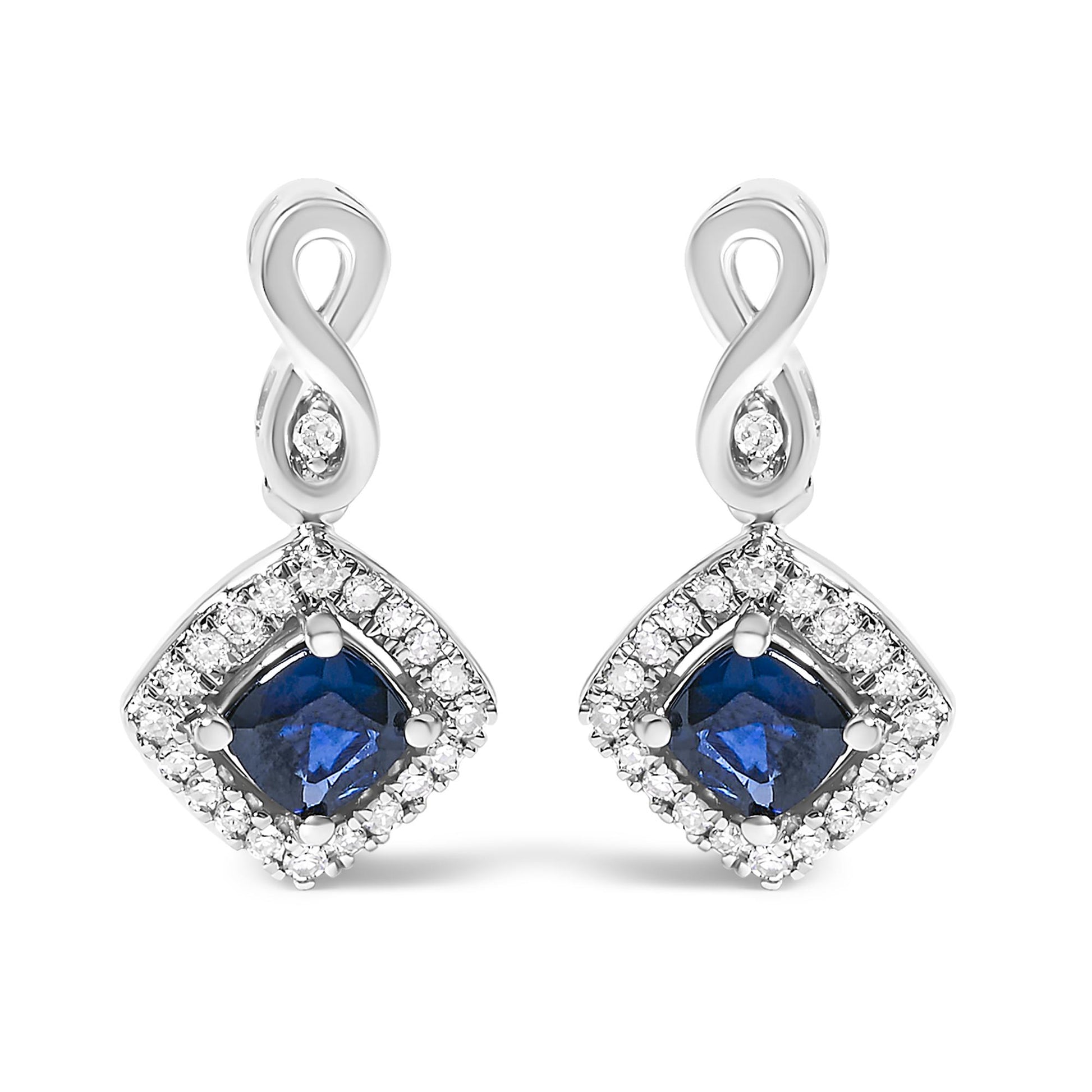 Front view of a pair of white metal earrings featuring an infinity loop at the top with a small white gemstone in the center, and a cushion-shaped blue gemstone surrounded by a border of round white gemstones in a prong setting.