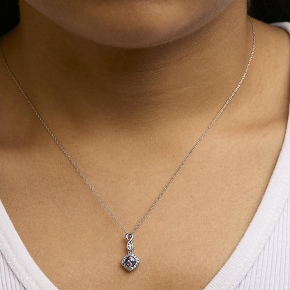 Necklace with a white metal chain, featuring a pendant with a blue cushion-shaped gemstone surrounded by small round white gemstones, shown worn on a model from the front angle.