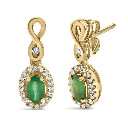 Close-up front and side view of yellow metal earrings with an infinity-shaped loop, featuring a prong-set oval green gemstone surrounded by a halo of small round white gemstones in a pave setting.