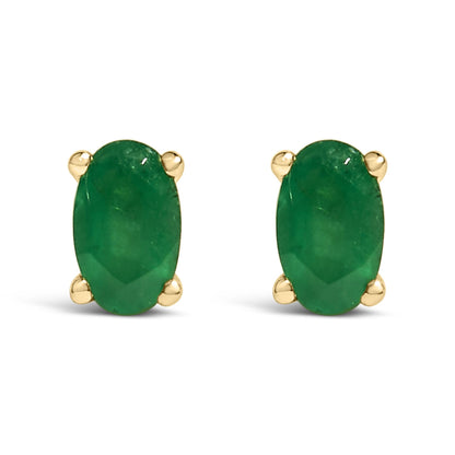 Front-facing shot of yellow metal stud earrings each featuring an oval-shaped green gemstone in prong settings.
