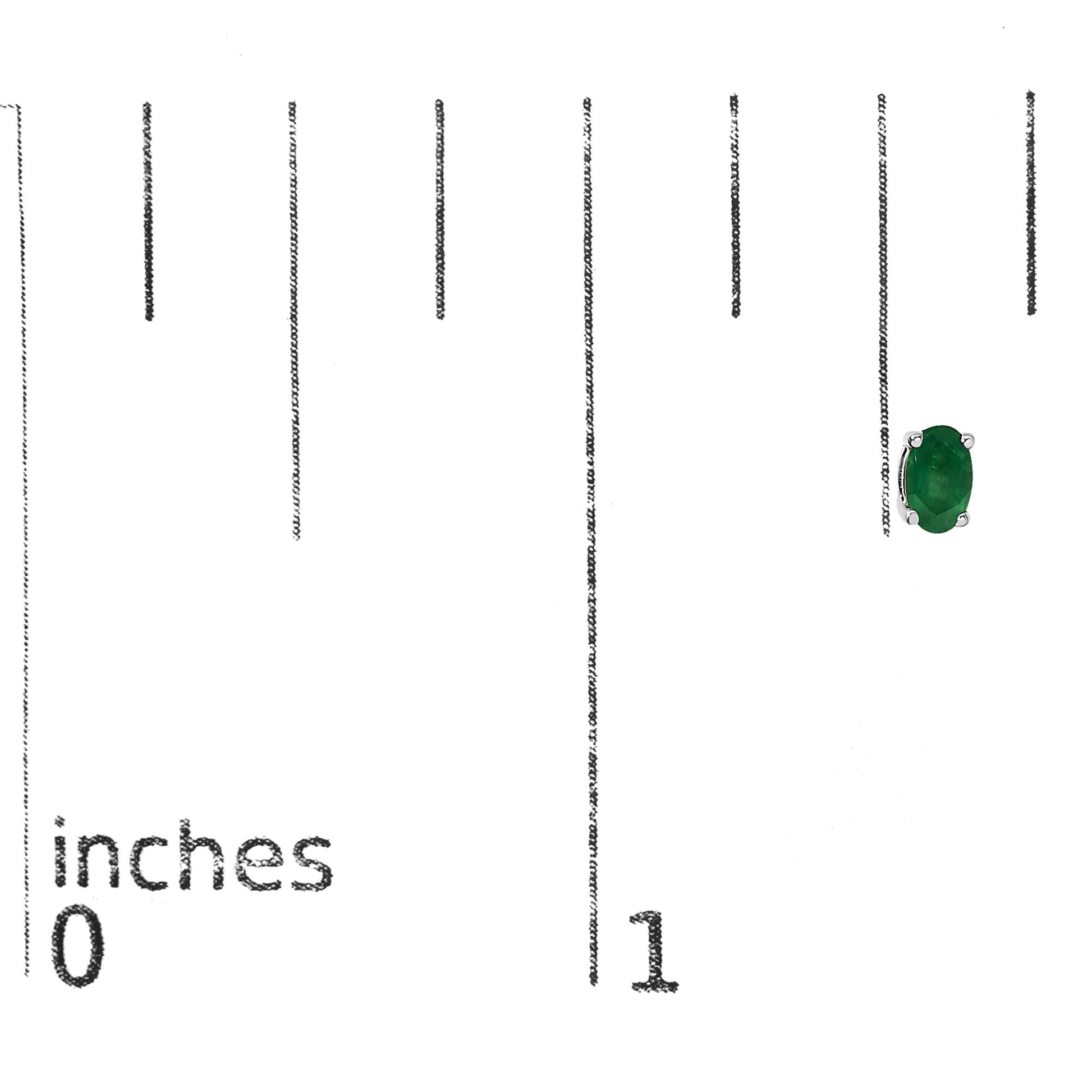 Close-up front angle of a single white metal earring with an oval green gemstone in a prong setting, shown on a ruler for size reference.