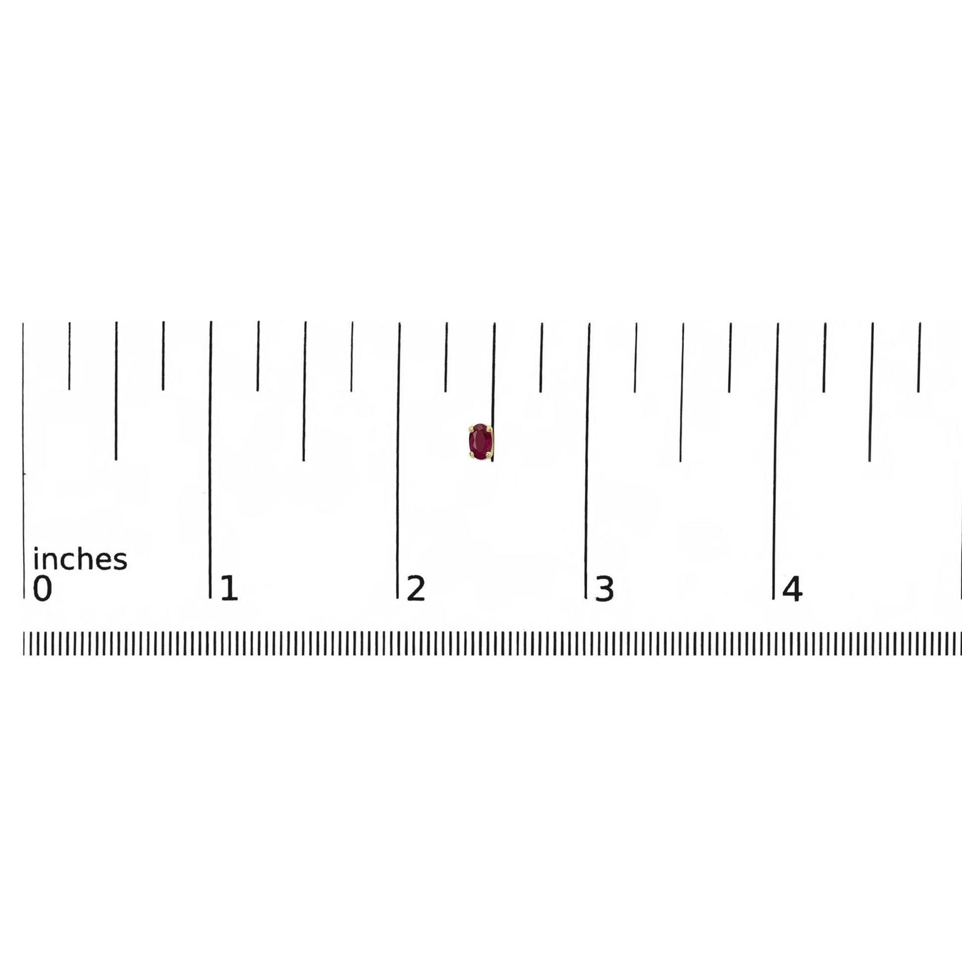 Close-up front view of yellow metal stud earring with oval red gemstone, shown on a ruler for size reference.
