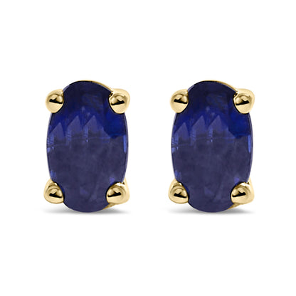 Front view of yellow metal stud earrings with oval-shaped blue gemstones in prong settings.