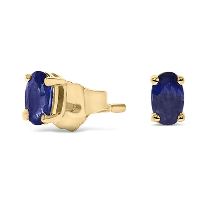 Pair of yellow metal stud earrings with oval blue gemstones in prong settings, shown from front and side angles on a white background.