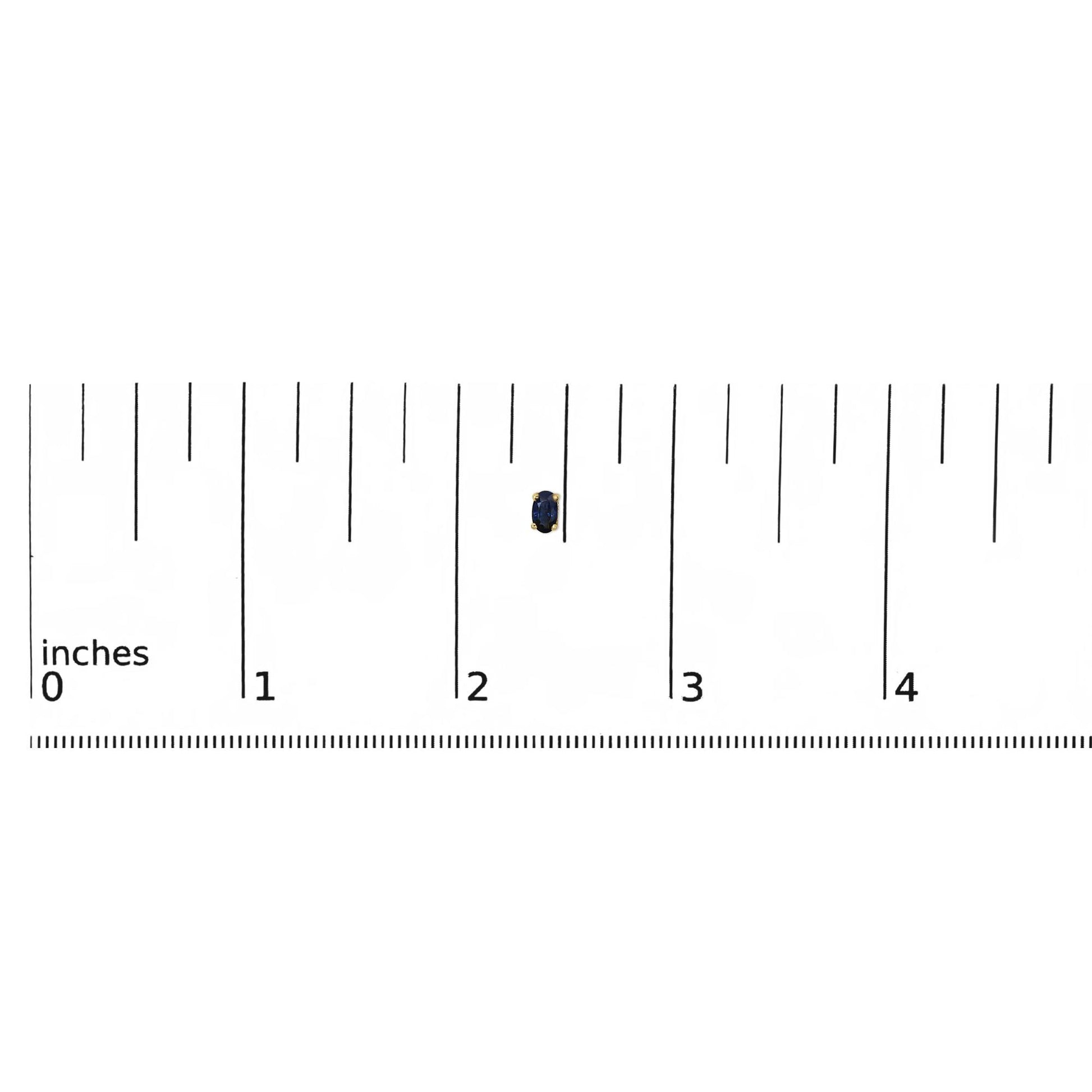 Close-up image of a single yellow metal earring with an oval blue gemstone in prong setting, shown on a ruler for size reference.
