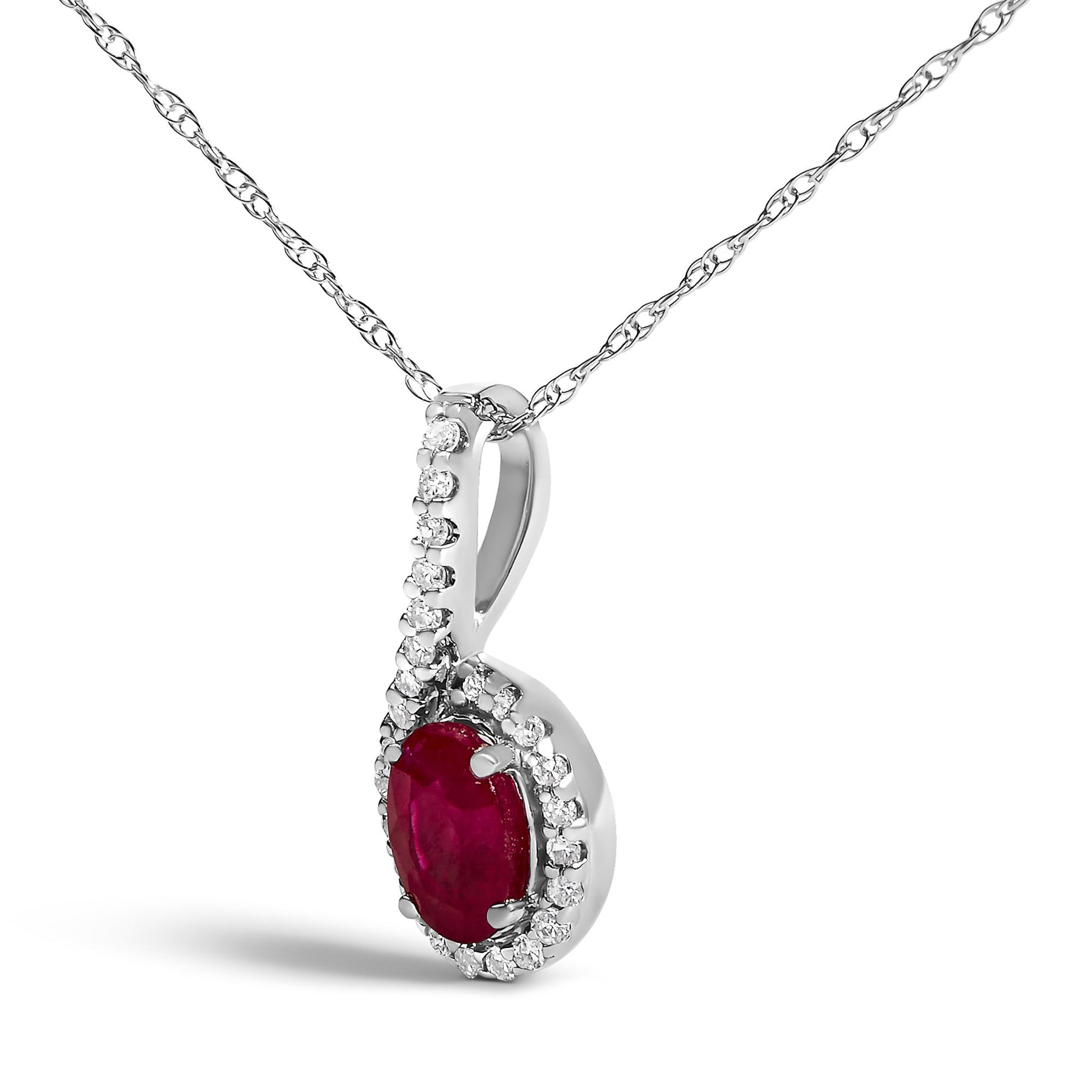 Close-up front angle of a white metal necklace pendant featuring a red oval gemstone surrounded by small white round gemstones in prong settings, shown against a white background.