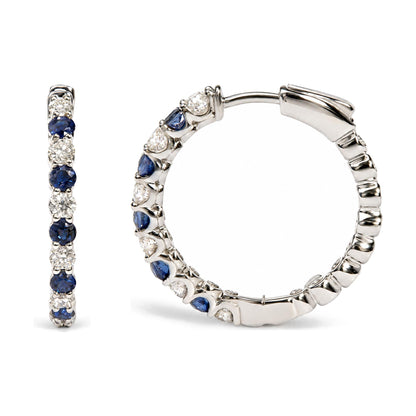 Close-up front and side angle of a white metal hoop earring featuring round white gemstones and round blue gemstones in prong settings.